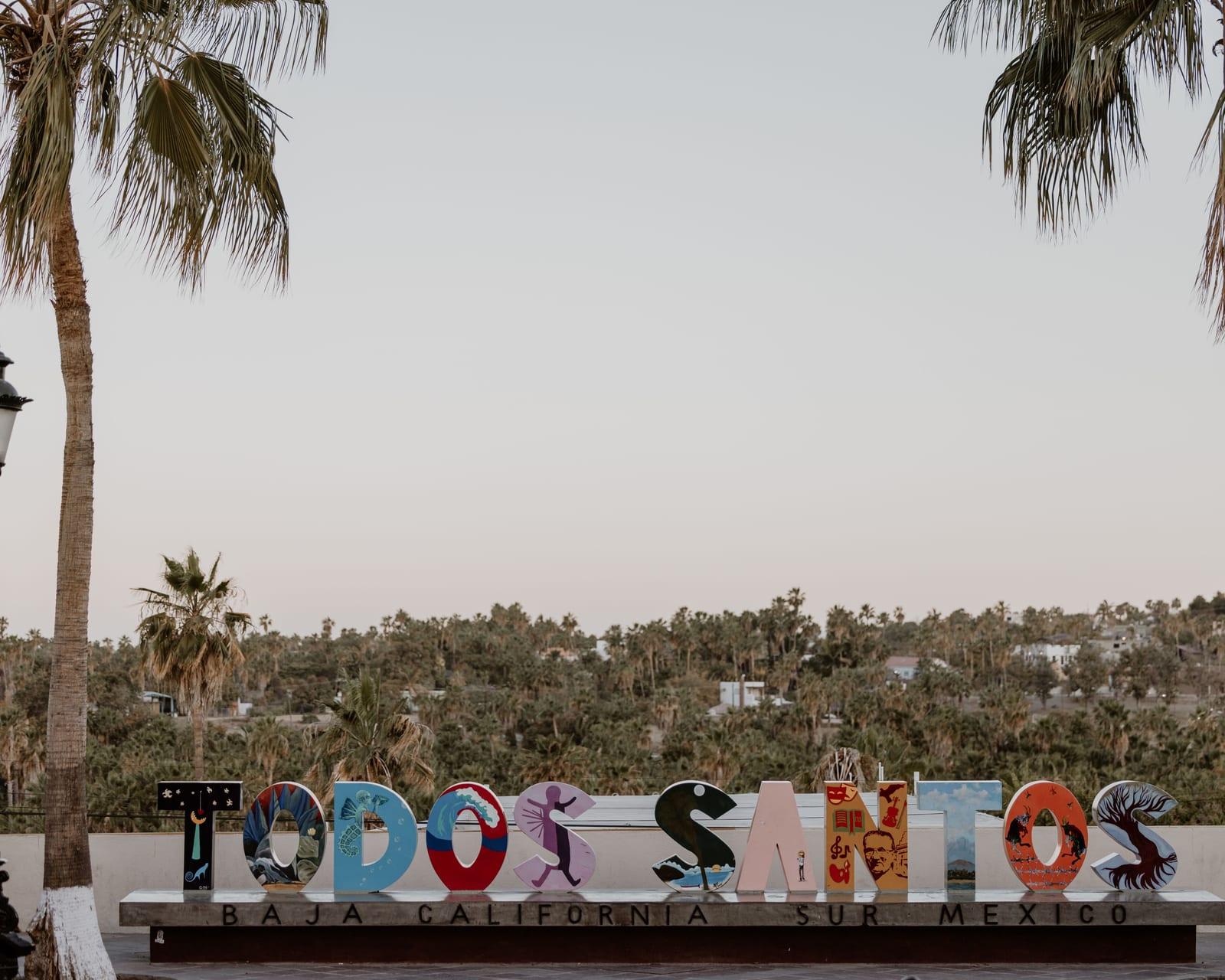 Colorful welcome sign and palm trees marking the entrance to Todos Santos, Baja California Sur, the artsy town behind this gallery walk.