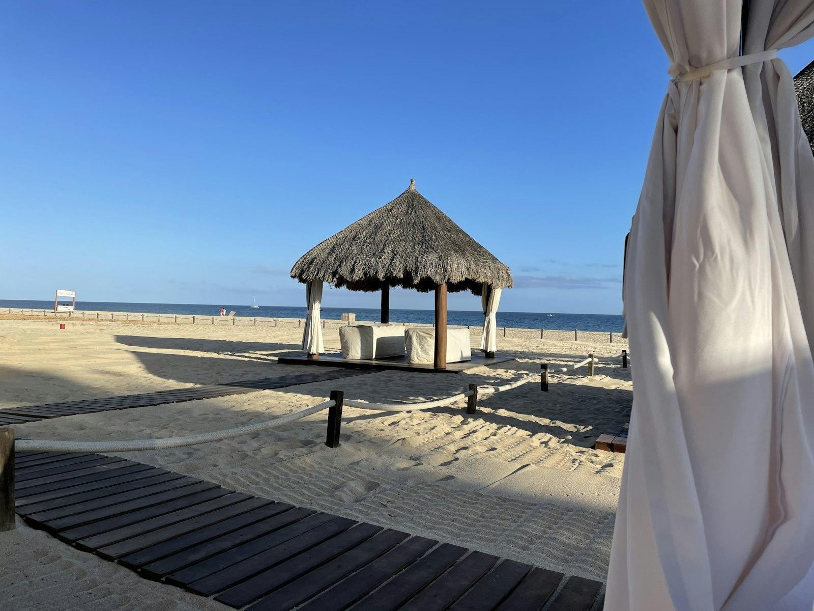 Palm-shaded gazebo on a sandy beach beside a resort in San José del Cabo