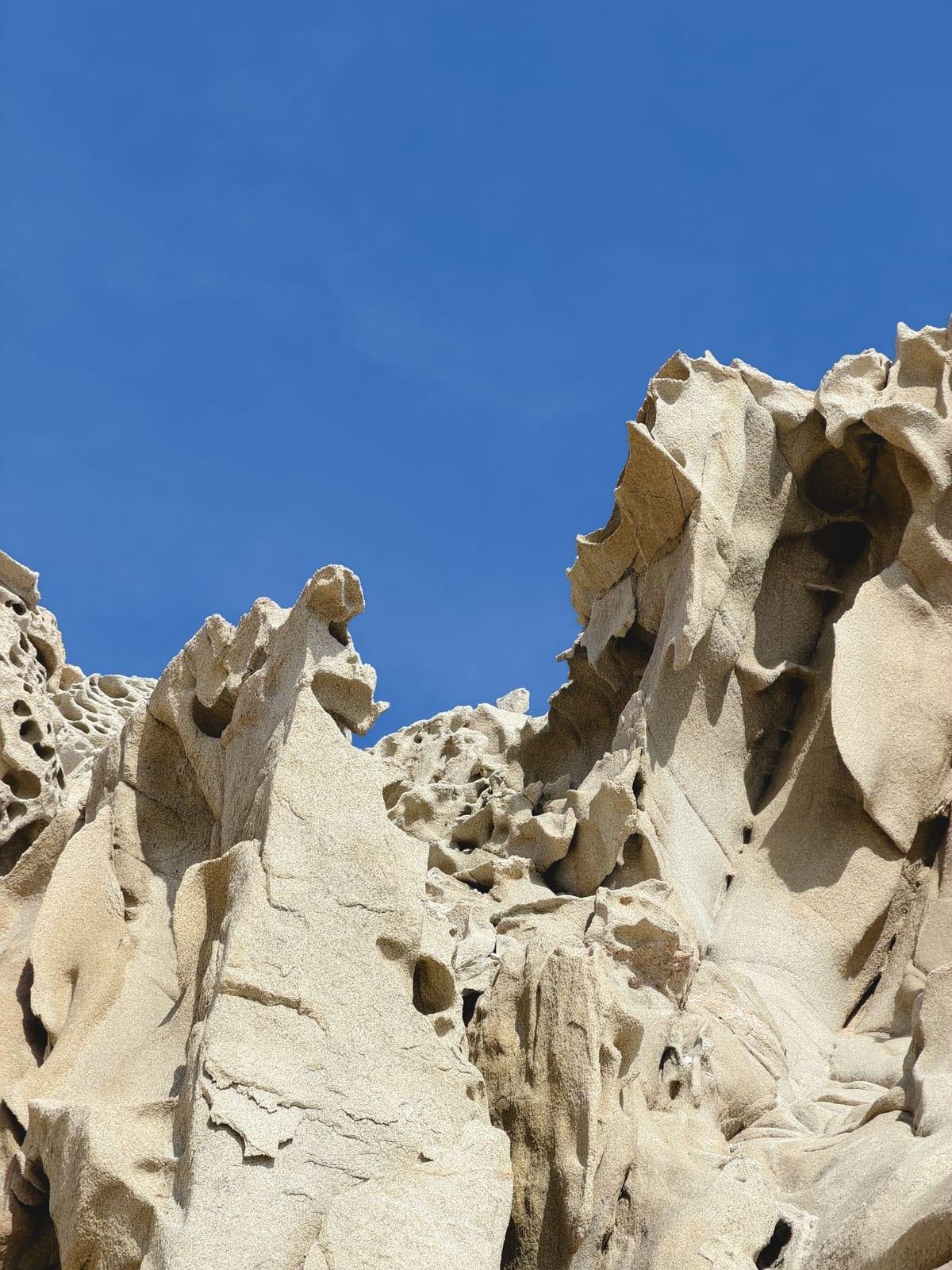 Sun-bleached desert rock formations rising against a clear blue sky in Cabo San Lucas