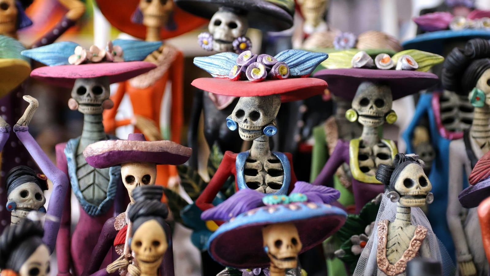 Rows of colorful hand-painted Catrina skeleton figurines for sale at a Cabo San Lucas market.