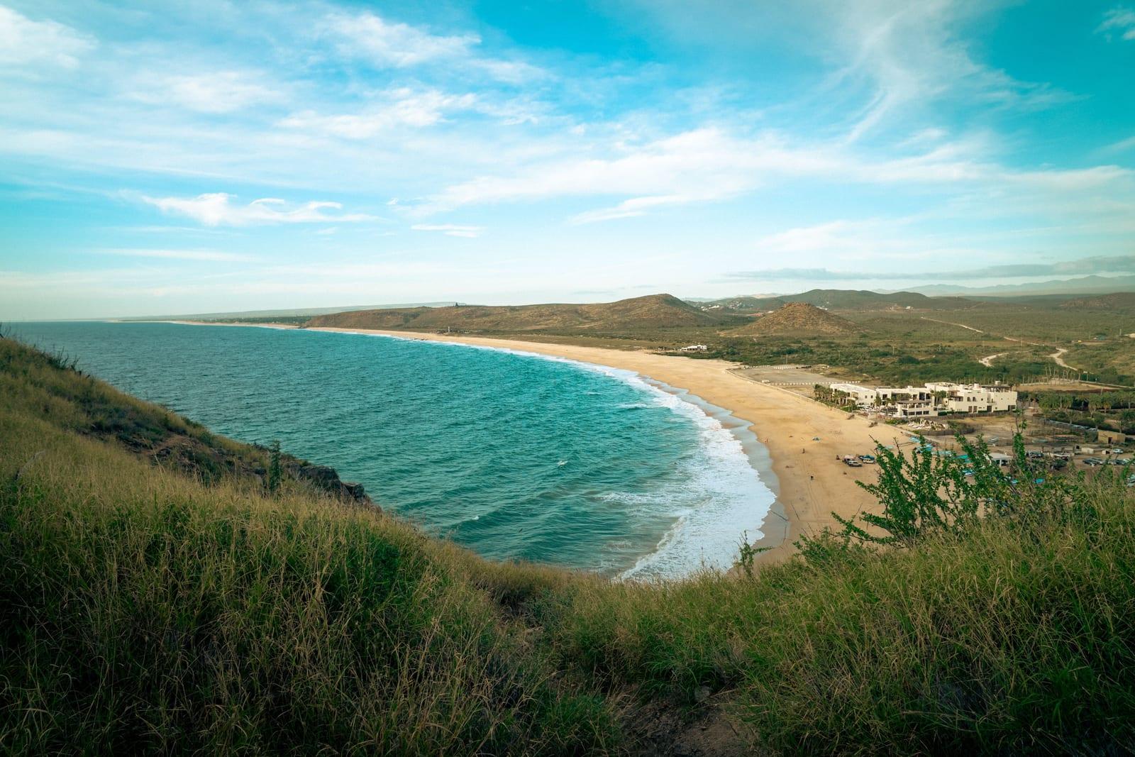 Playa Todos Santos, B.C.S., a wide sandy beach with lush greenery along the Pacific coast in Todos Santos.